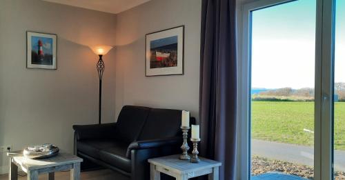 ein Wohnzimmer mit einem schwarzen Ledersessel und einem Fenster in der Unterkunft Ferienhaus Bella Vista in Gelting