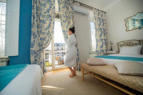 a woman standing in a bedroom looking out the window at House 52 Boutique Hotel in Tbilisi City