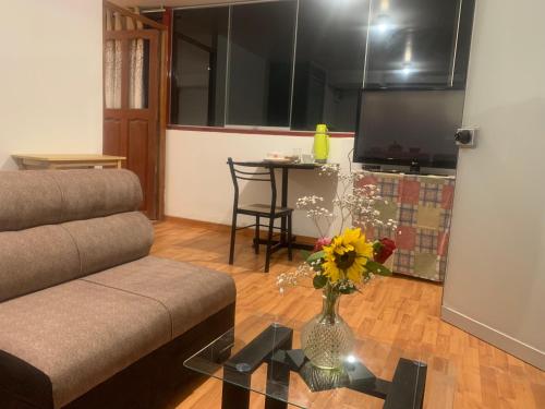 a living room with a couch and a vase of flowers on a table at Summit Viewpoint House San Blas in Cusco