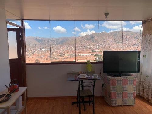 a room with a large window with a table and a television at Summit Viewpoint House San Blas in Cusco