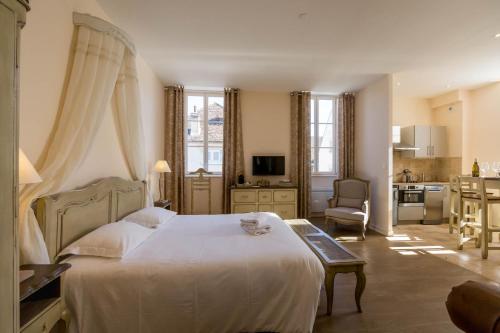 a bedroom with a large white bed and a kitchen at Le Cara Alya 1G in Beaune