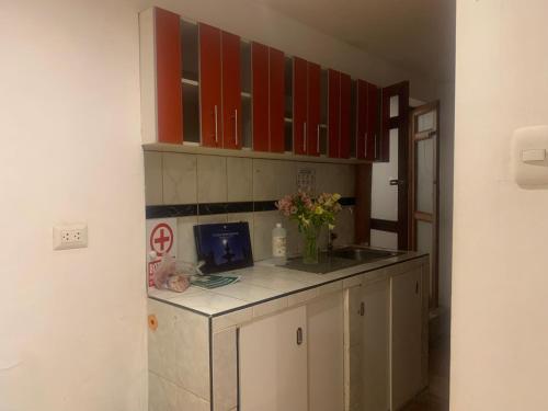 a kitchen with red cabinets and a vase of flowers on a counter at Summit Viewpoint House San Blas in Cusco