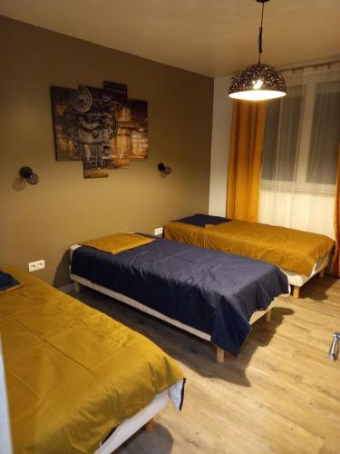 a bedroom with three beds and a chandelier at Les gîtes de la commanderie de Saint Jean SCAFER in Beynat