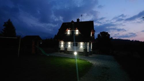 a house lit up at night with lights on it at Jurgowski Domek in Jurgów