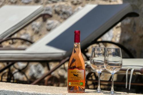 - une bouteille de vin et deux verres sur une table dans l'établissement Mas en Baronnies Provençales, à Eygaliers