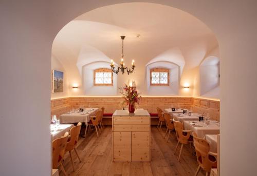 a dining room with tables and chairs and a chandelier at Parkhotel Margna Superior in Sils Maria