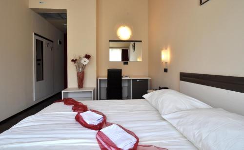 a bedroom with a white bed with red bows on it at Hotel Fontana in Buzet
