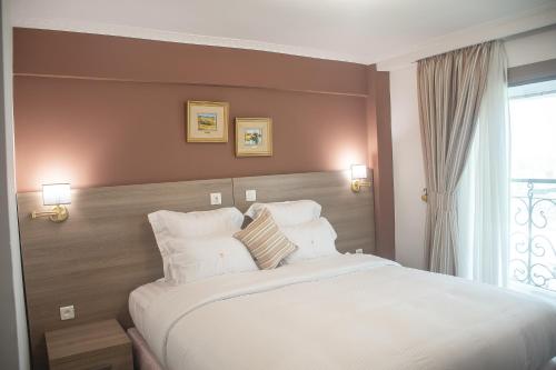 um quarto com uma grande cama branca e uma janela em FAYA Hotel em Douala