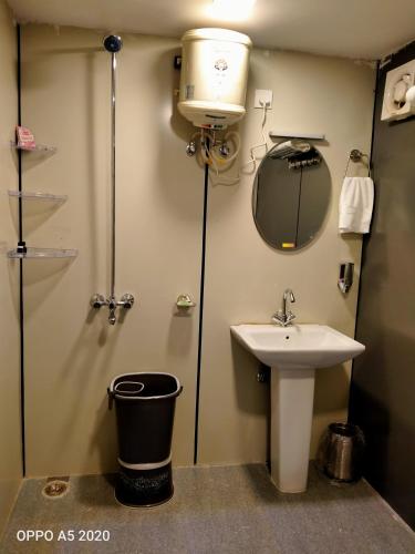 a bathroom with a sink and a shower and a mirror at Oak Retreat Huts in Shimla