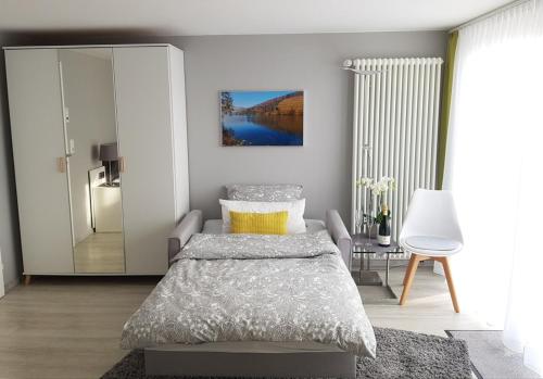 ein Schlafzimmer mit einem Bett, einem Stuhl und einem Spiegel in der Unterkunft Gästezimmer-Apartment Heidi Hönl in Buergstadt
