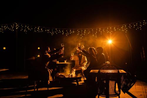 a group of people sitting around a fire with wine glasses at Kozjanski dvor in Podčetrtek