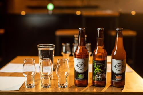 four bottles of beer and glasses on a table at Kozjanski dvor in Podčetrtek
