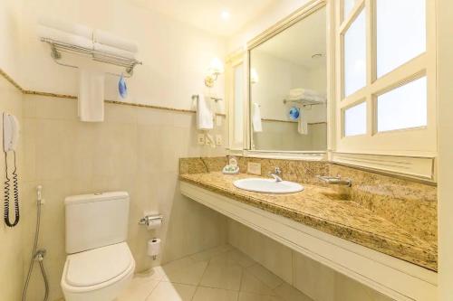 a bathroom with a toilet and a sink and a mirror at Studio IL Campanario Villagio Resort in Florianópolis