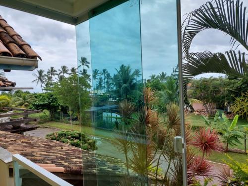 a glass facade of a house with palm trees at Pousada Vitória in Ilhéus