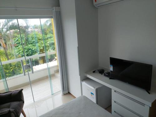 a living room with a flat screen tv and a window at Pousada Vitória in Ilhéus