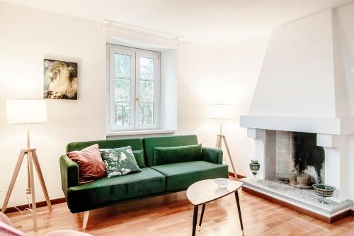 ein grünes Sofa im Wohnzimmer mit Kamin in der Unterkunft Salorino Apartments by Quokka 360 - with a view of nature in Mendrisio