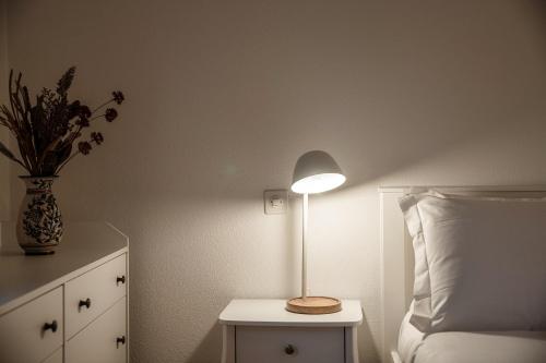 a lamp on a night stand next to a bed at Salorino Apartments by Quokka 360 - with a view of nature in Mendrisio