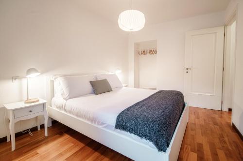 a white bedroom with a white bed and a night stand at Salorino Apartments by Quokka 360 - with a view of nature in Mendrisio