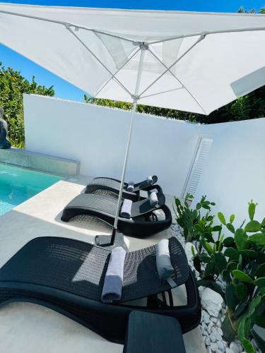 two lounge chairs under an umbrella next to a swimming pool at Casa Almea Sisal in Sisal