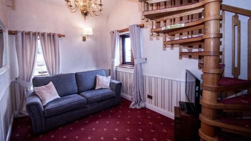 a living room with a blue couch and a spiral staircase at Leeming Wells in Haworth
