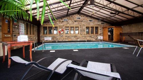 a large swimming pool with chairs in a building at Leeming Wells in Haworth