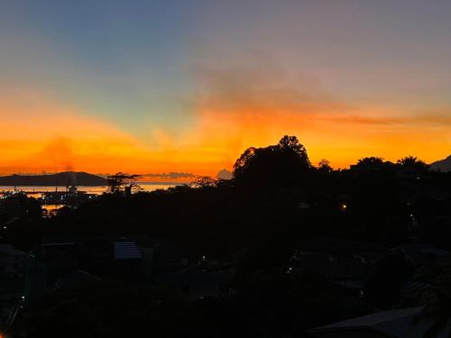 a sunset over a city with trees in the foreground at Hilltop Boutique Hotel in Victoria