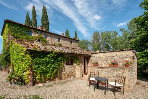 an old stone building with two chairs and a table at Castello di Bossi in Castelnuovo Berardenga