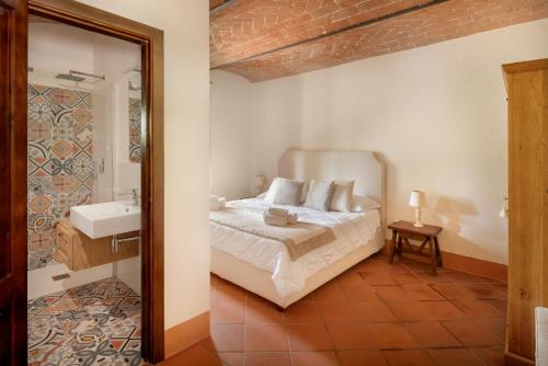 a bedroom with a bed and a bathroom with a sink at Castello di Bossi in Castelnuovo Berardenga