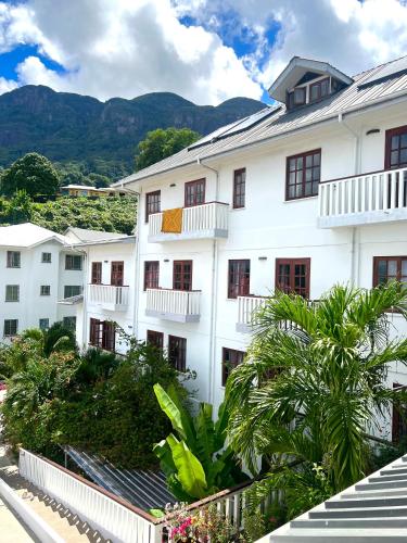 a white building with trees and mountains in the background at Hilltop Boutique Hotel in Victoria