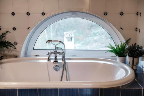 a bath tub in a bathroom with a window at Salorino Apartments by Quokka 360 - with a view of nature in Mendrisio