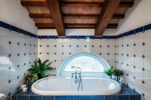 a bathroom with a tub and an arched window at Salorino Apartments by Quokka 360 - with a view of nature in Mendrisio
