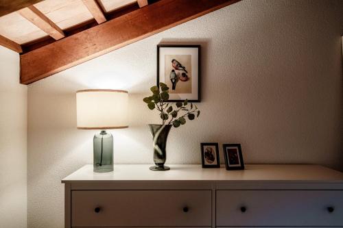 a table with a lamp and a vase with a plant on it at Salorino Apartments by Quokka 360 - with a view of nature in Mendrisio