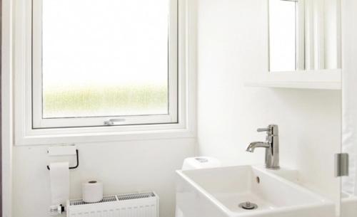 biała łazienka z umywalką i oknem w obiekcie Immaculate 2-Bed House at the beach 12H w mieście Brenderup