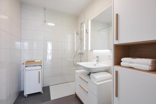 a white bathroom with a sink and a mirror at Redlok in Garmisch-Partenkirchen