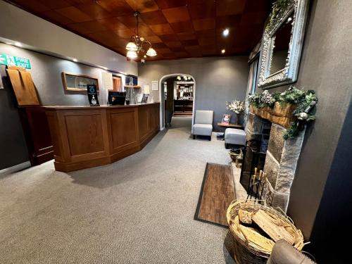 a waiting room with a fireplace and a bar at Stirk House Hotel in Clitheroe