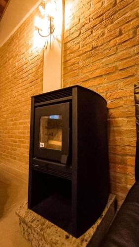 a black tv sitting in a room with a brick wall at Espaço Viverde Penedo in Penedo