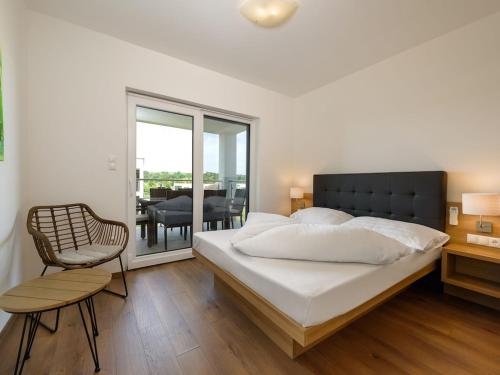 1 dormitorio con 1 cama, 1 silla y balcón en Heritage Apartment in Lutzmannsburg with Swimming Pond, en Zsira