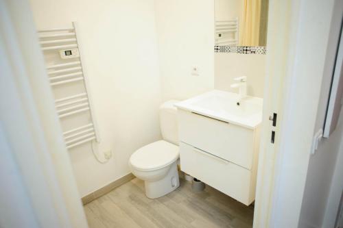 a white bathroom with a toilet and a sink at Une bulle de quiétude proche de Paris et Créteil in Bonneuil-sur-Marne