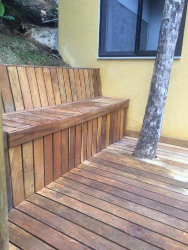 a wooden bench on a deck with a tree at Espaço Viverde Penedo in Penedo
