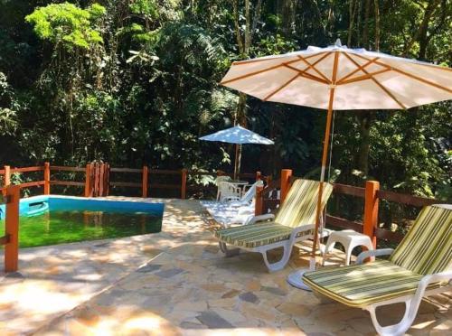 a patio with chairs and an umbrella and a pool at Espaço Viverde Penedo in Penedo