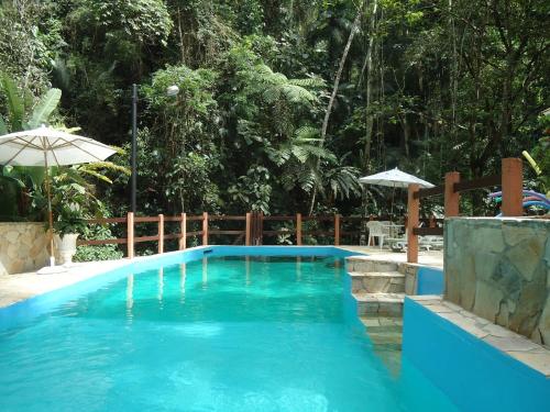 a blue swimming pool with a fence and an umbrella at Espaço Viverde Penedo in Penedo