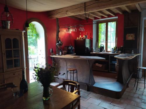 a kitchen with red walls and a table and chairs at Les Amis de Gaure in Rouffiac-dʼAude