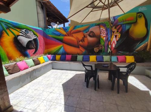 a table and chairs in front of a mural at Pousada Areias do Pero in Cabo Frio