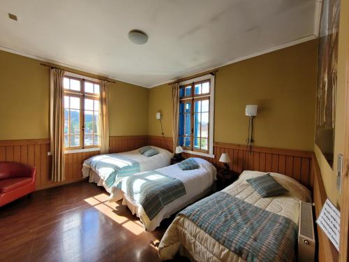una camera da letto con due letti e una sedia rossa di Hotel San Giorgio a Capitán Pastene