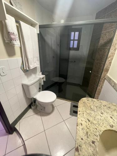 a bathroom with a white toilet and a shower at Pousada Areias do Pero in Cabo Frio