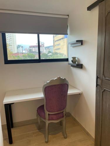 a desk with a purple chair and a window at Hotel 14-04 in Cali