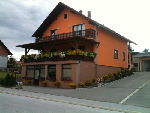 ein orangefarbenes Gebäude mit Balkon und Blumen darauf in der Unterkunft Apartment Pavlešić in Slunj