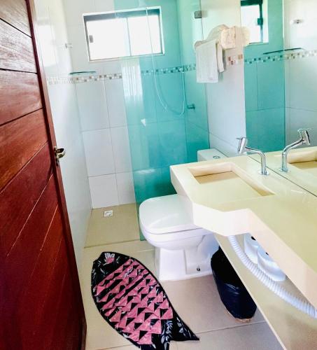 a bathroom with a toilet and a sink and a mirror at Encanto das Flores in Pipa