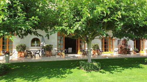 a courtyard with tables and chairs under a tree at Les Loges de Saint Eloi in Pontlevoy