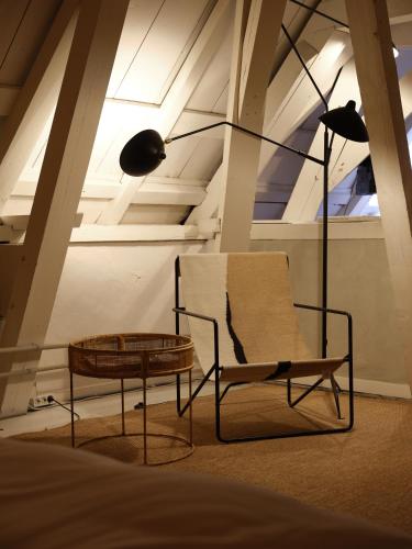a chair and a table and a lamp in a room at Eco Hotel Plantage Rococo in Velsen-Zuid